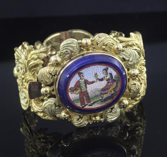 An ornate 19th century pierced pinchbeck hinged bracelet with central oval micro mosaic panel,